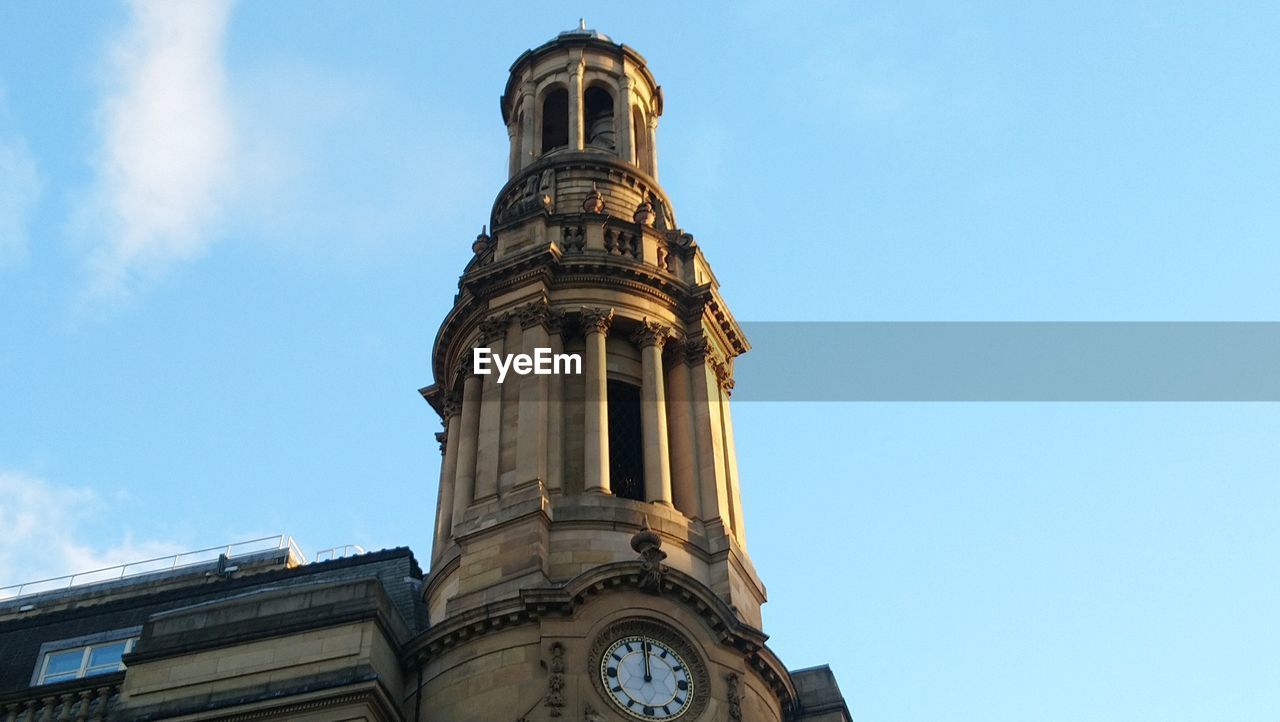 Low angle view of clock tower against blue sky