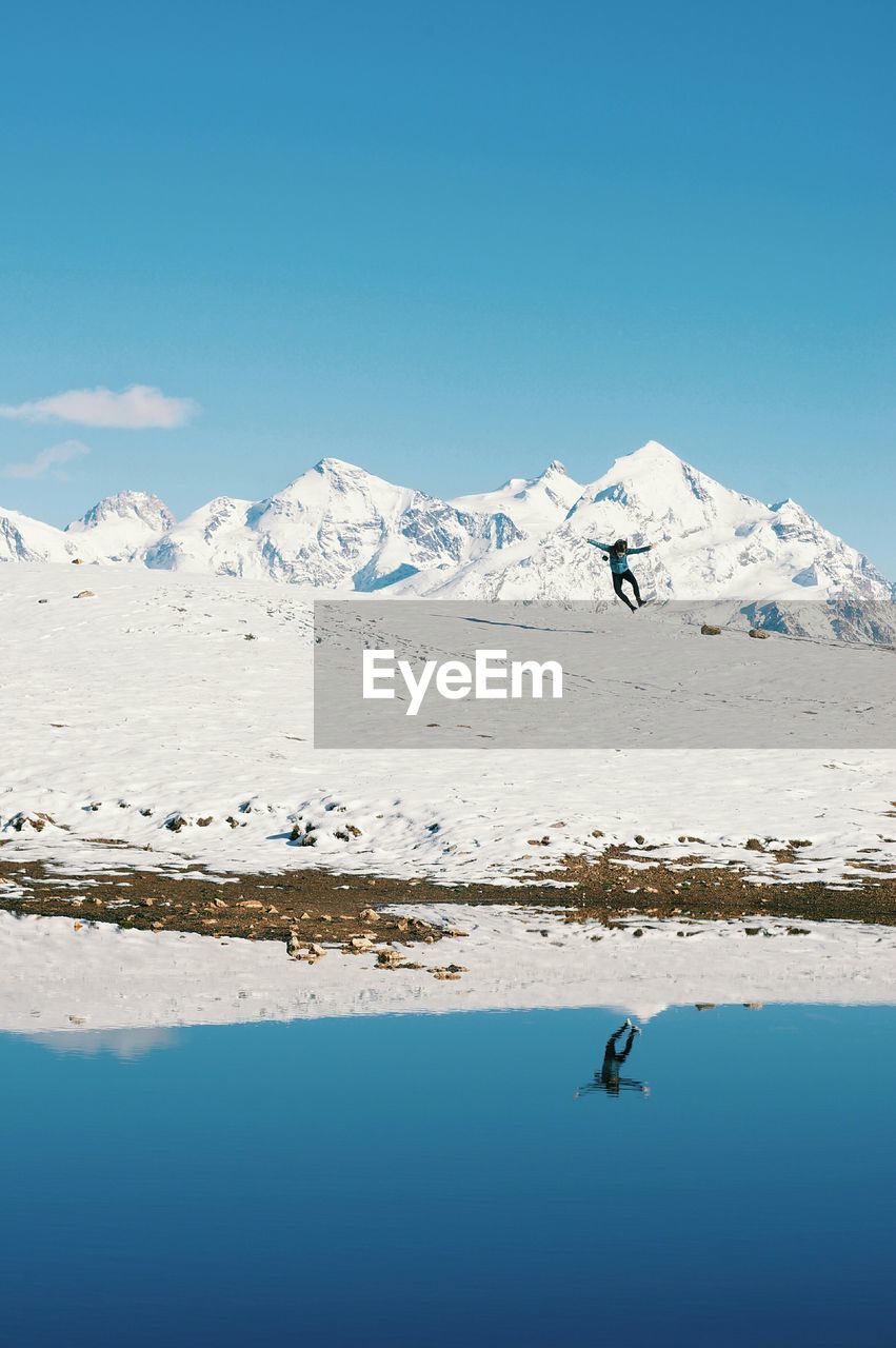 Full length of person jumping on snow covered field