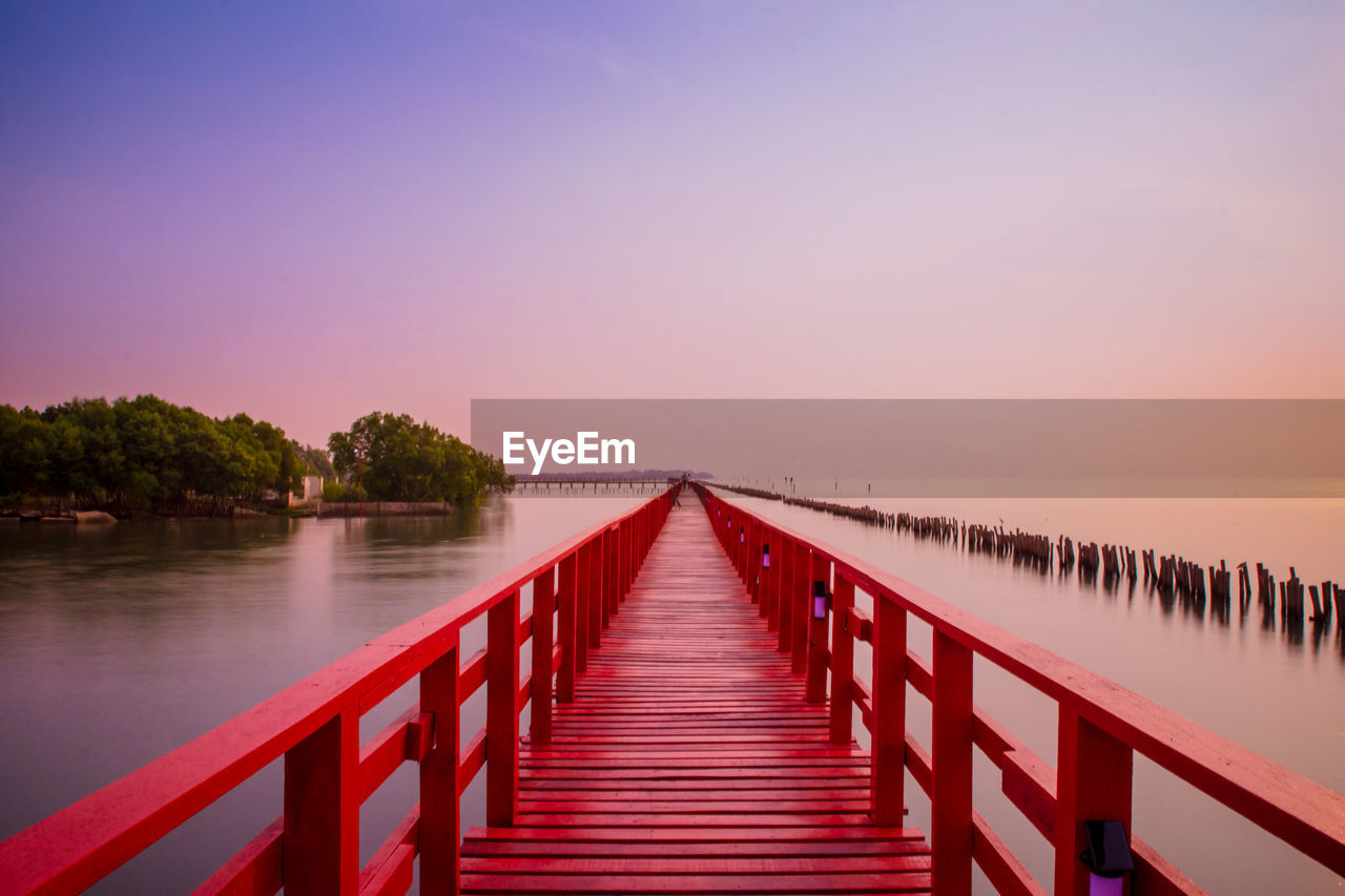 Pier over sea against sky during sunset