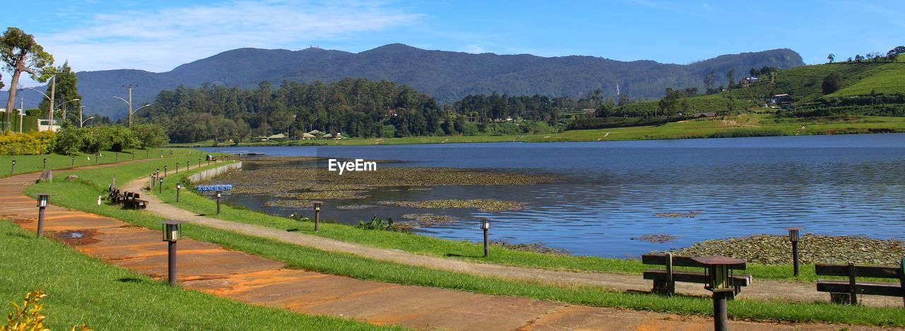 Scenic view of field by lake against sky