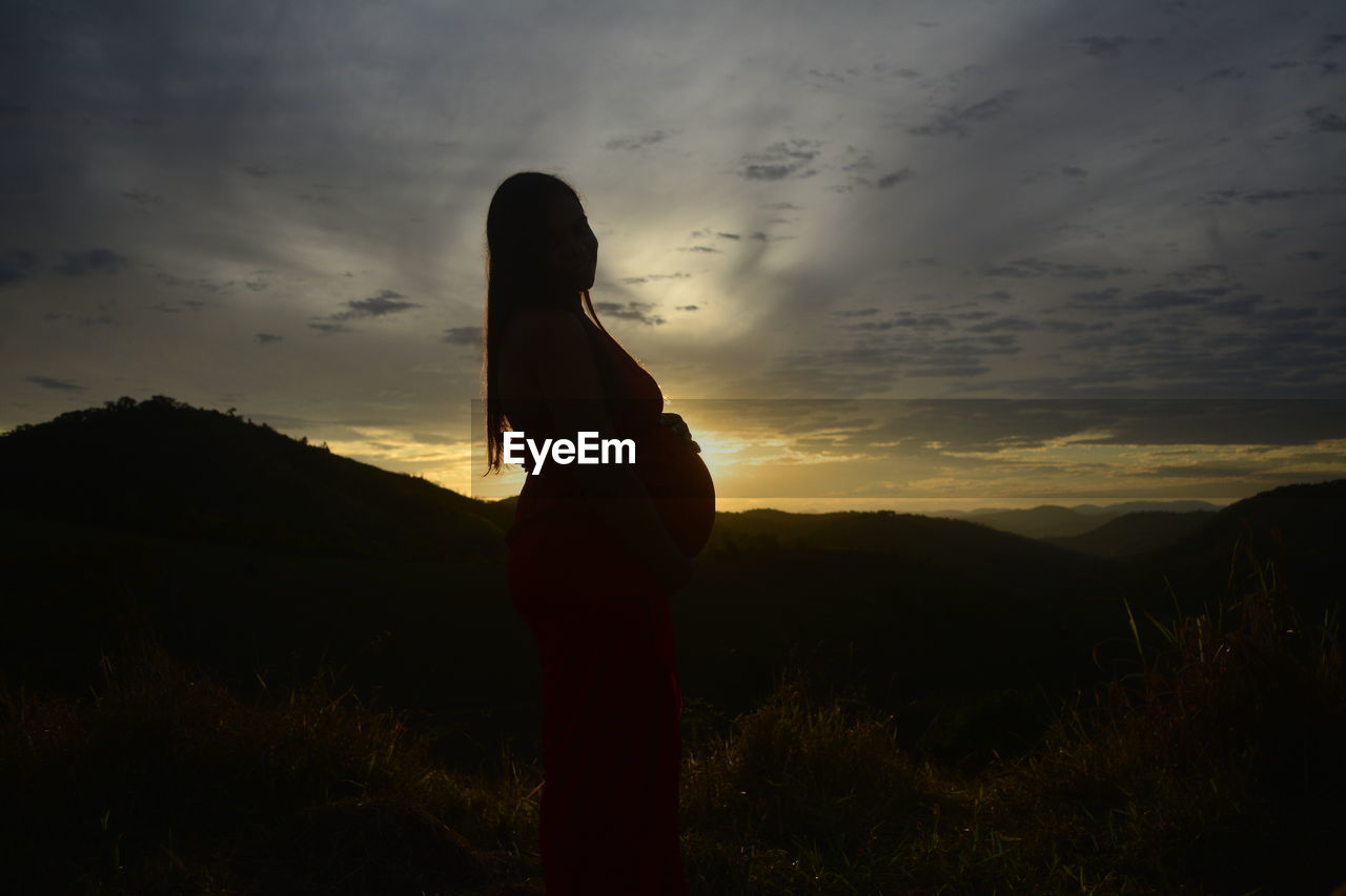 Silhouette person standing on field against sky during sunset