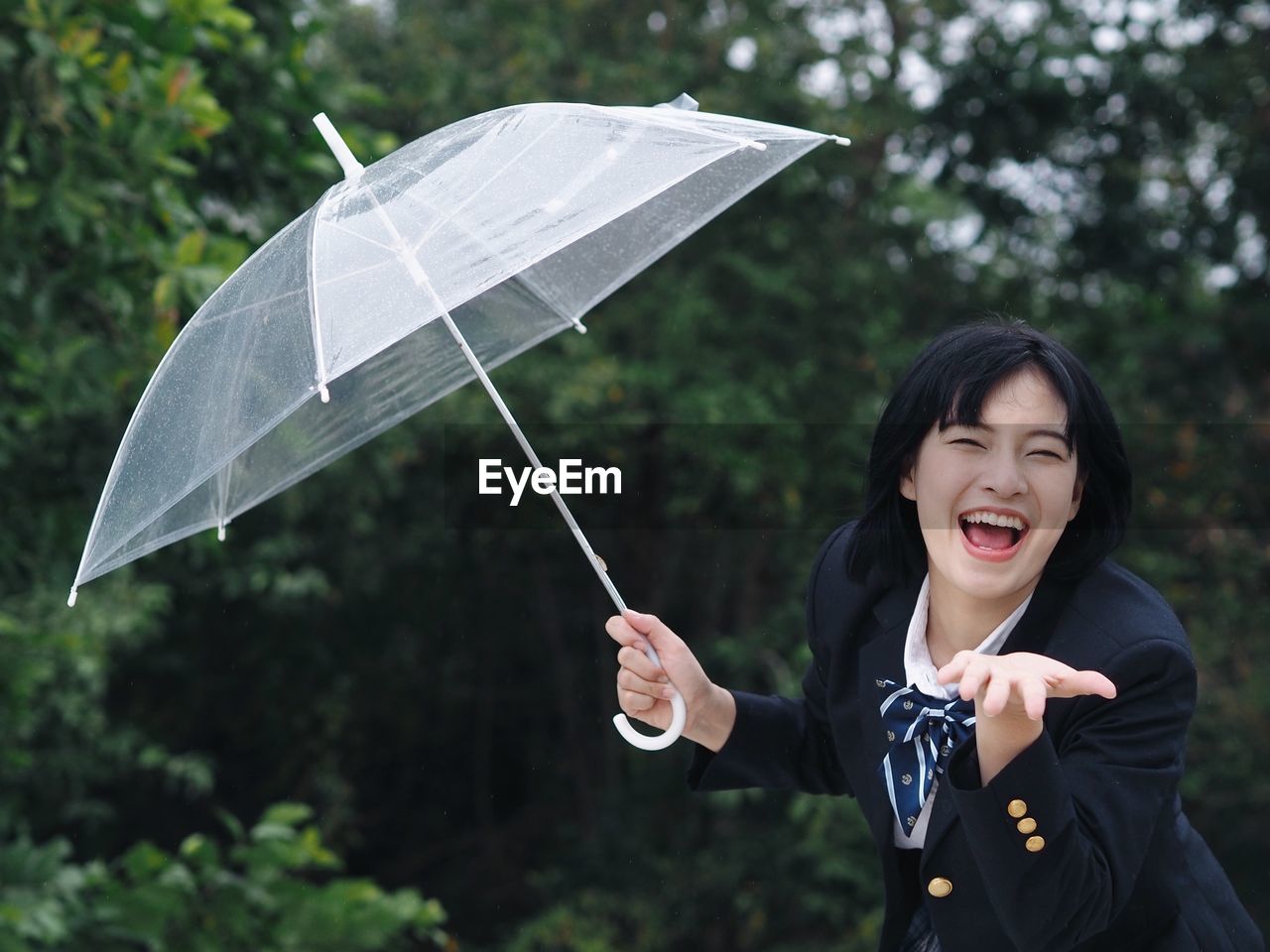 Portrait of happy woman holding umbrella during rainy season