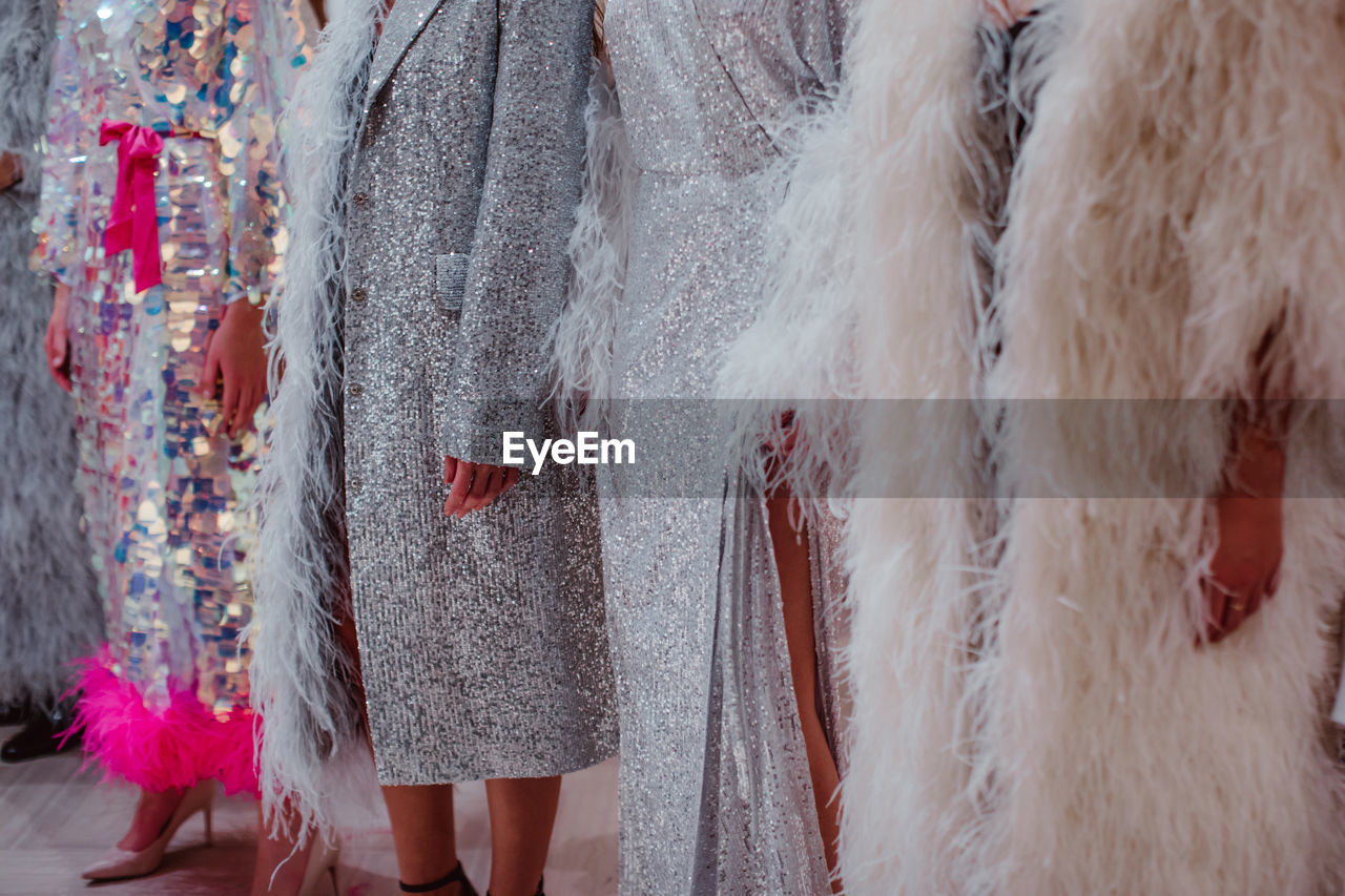 Silhouettes of fashion models on backstage dressed in a long haute couture boudoir dresses outfits. 