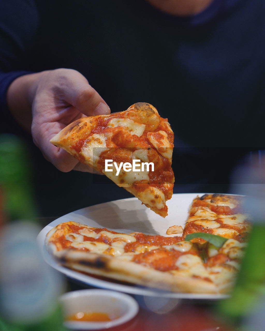 CLOSE-UP OF PERSON HAND HOLDING PIZZA