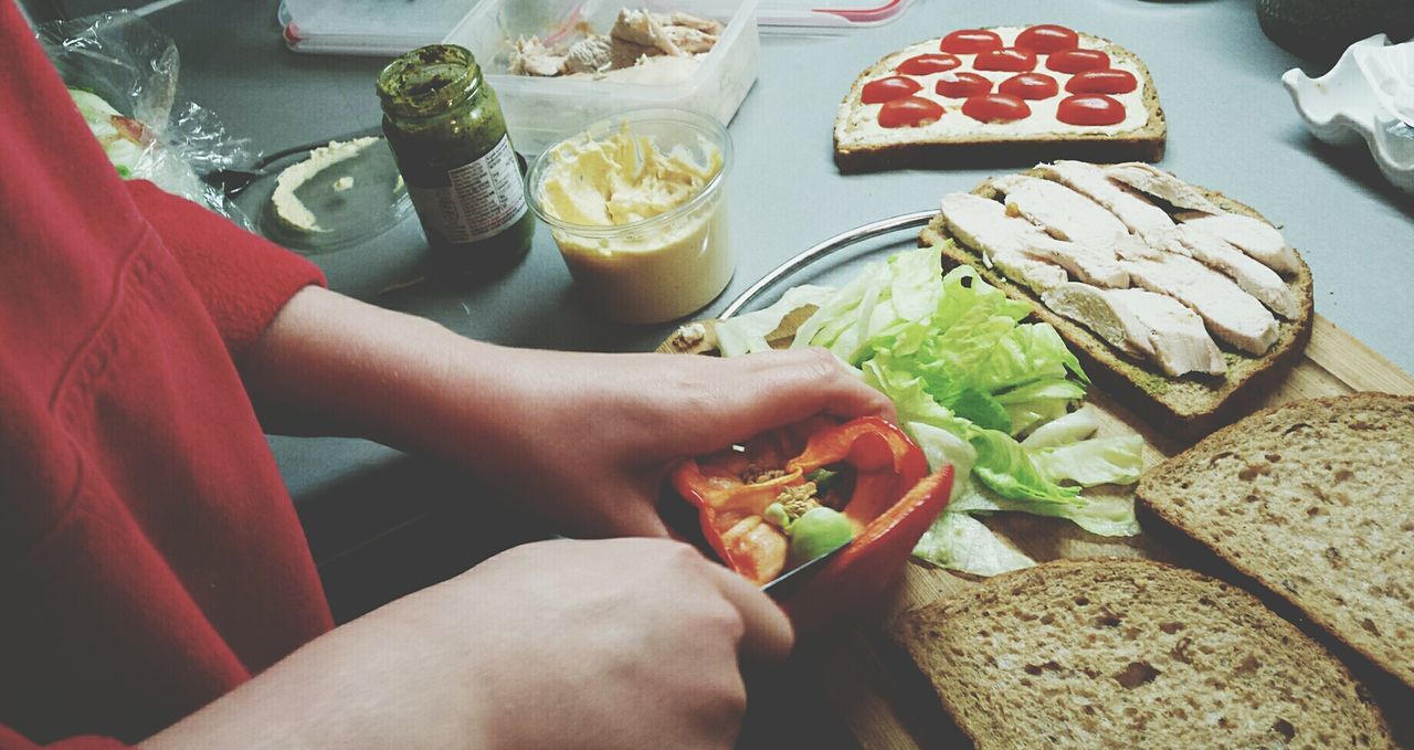 Woman preparing sandwich while standing at kitchen