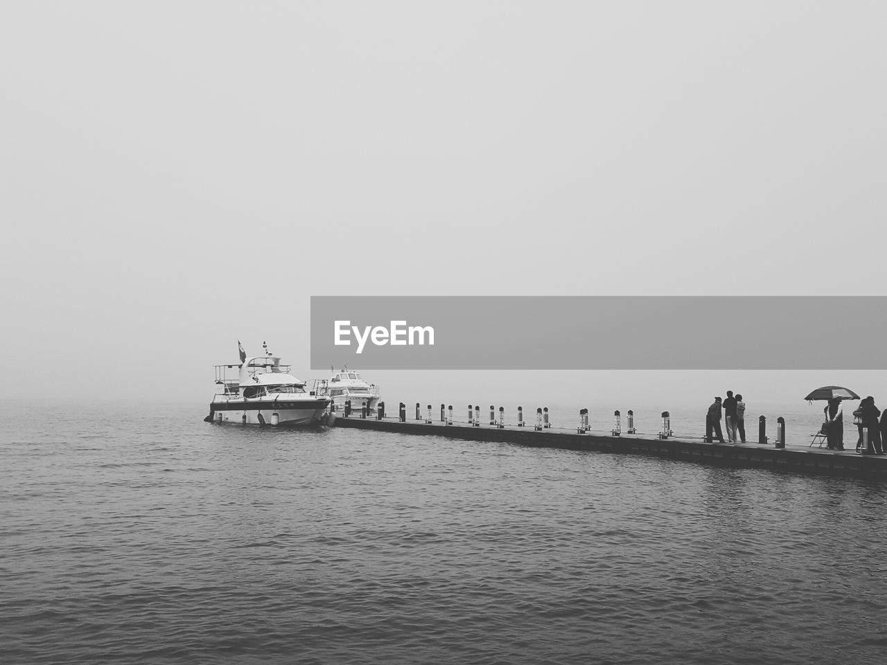 People walking on jetty at calm sea