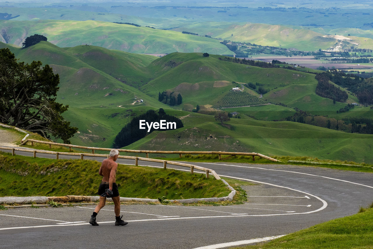 Rear view of a man walking on road