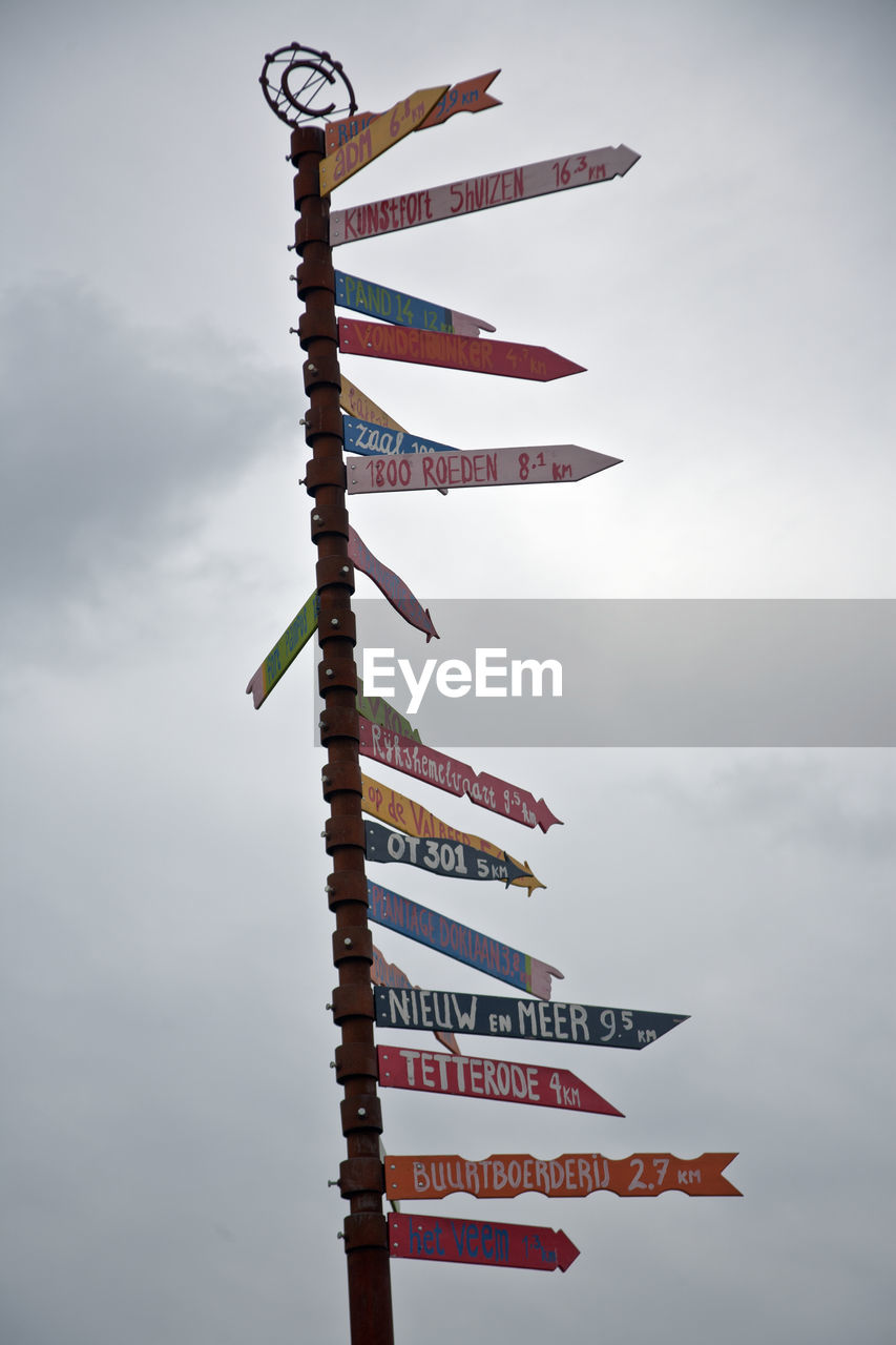 Low angle view of various information signs against sky