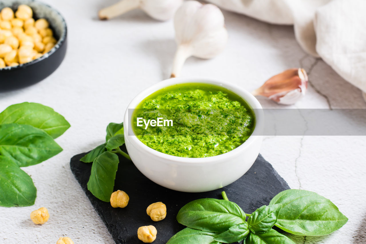 Fresh basil pesto sauce in a bowl on the table. homemade savory snacks. close-up