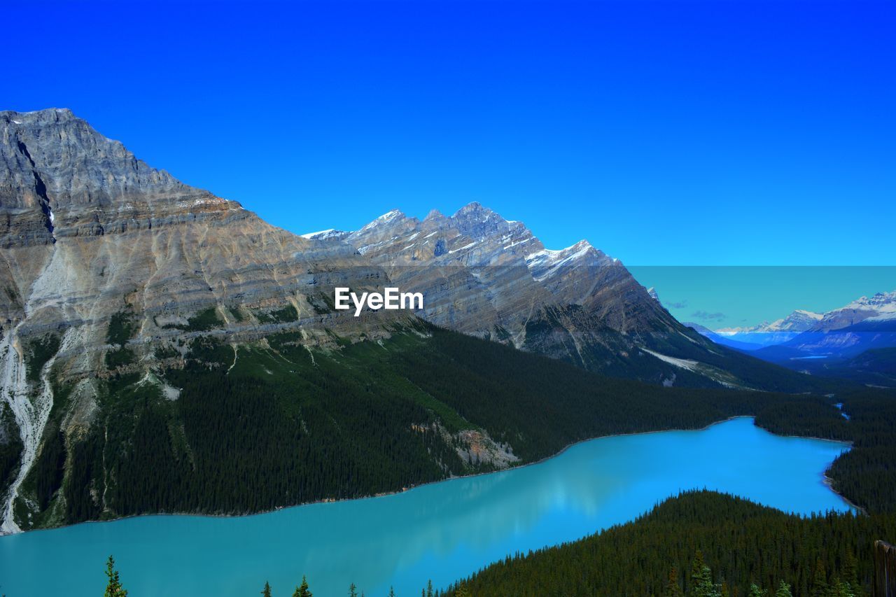 Scenic view of river and mountains against clear blue sky