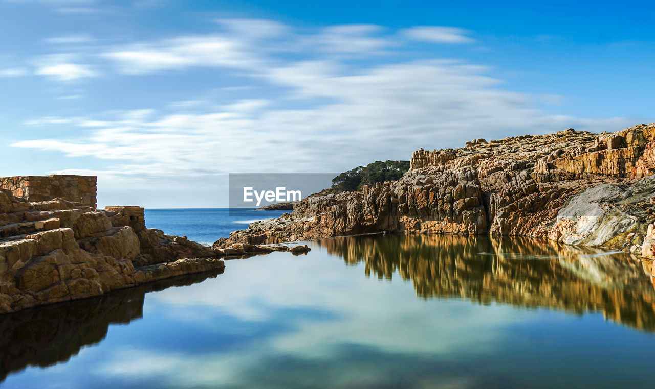 Rock formations by sea against sky