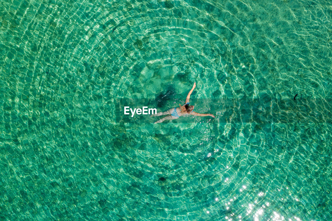 Aerial view of a girl floating in the turquoise sea on the cres island, adriatic sea, croatia