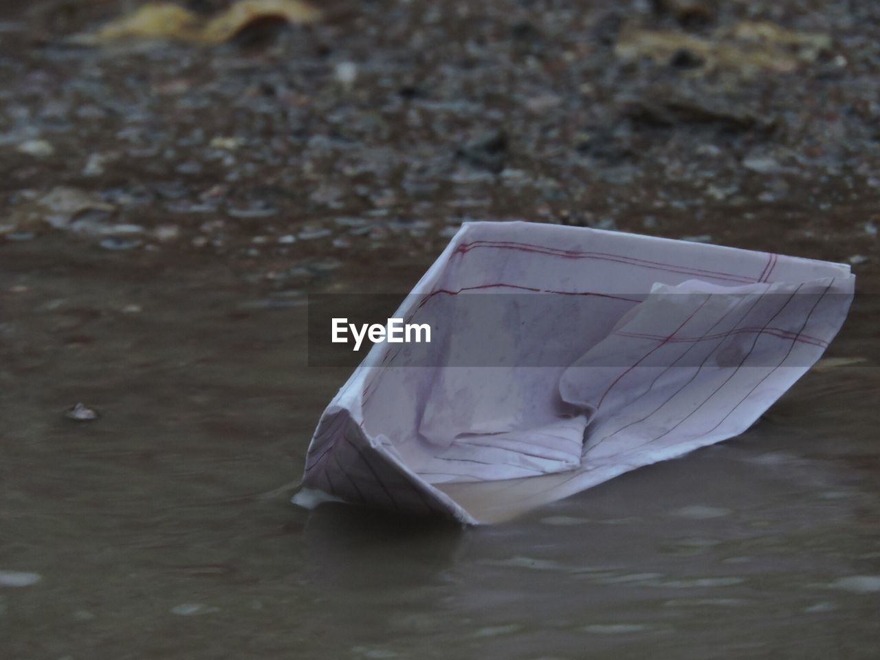 Paper boat in puddle