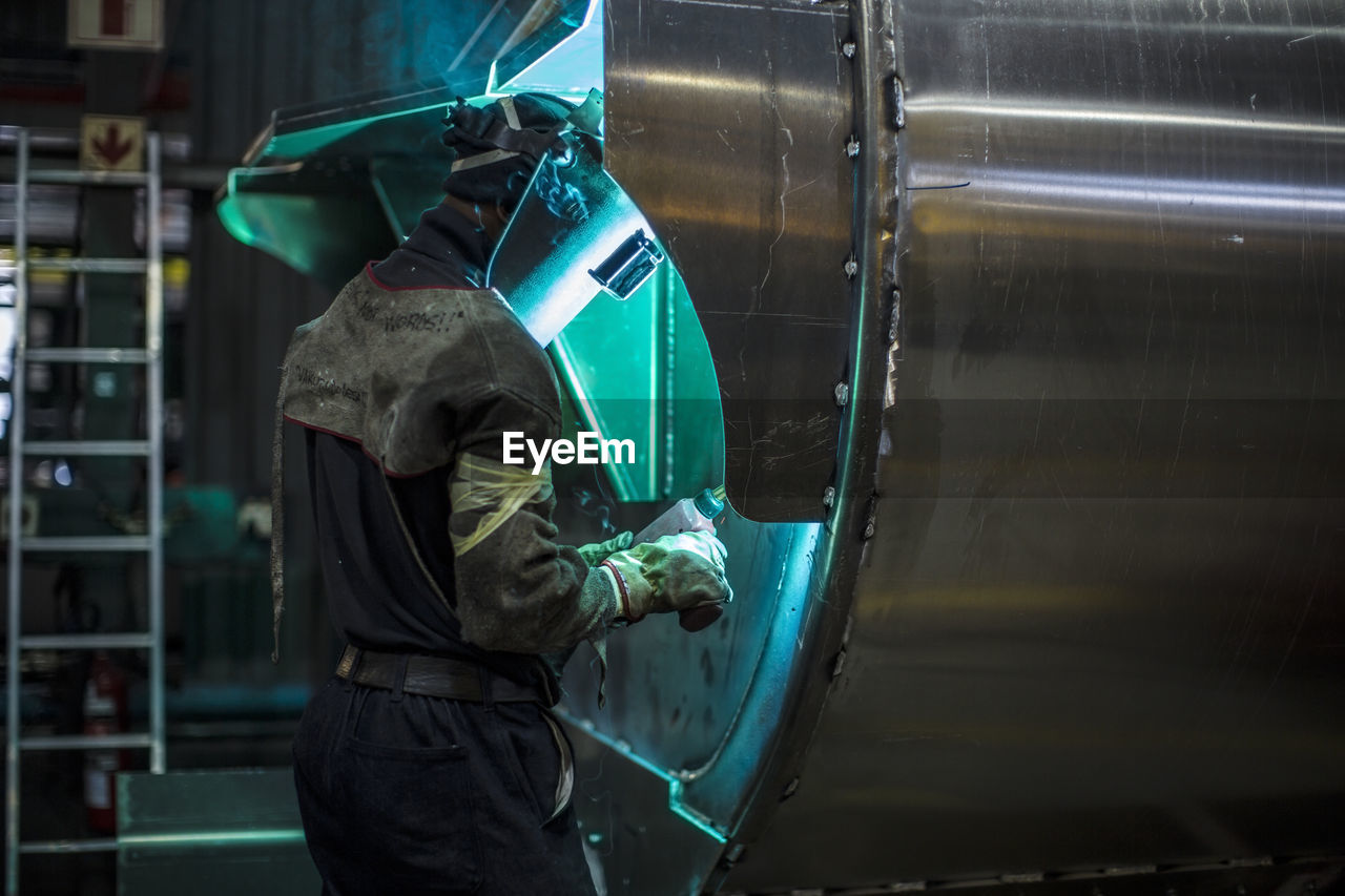 Man welding steel tank in factory