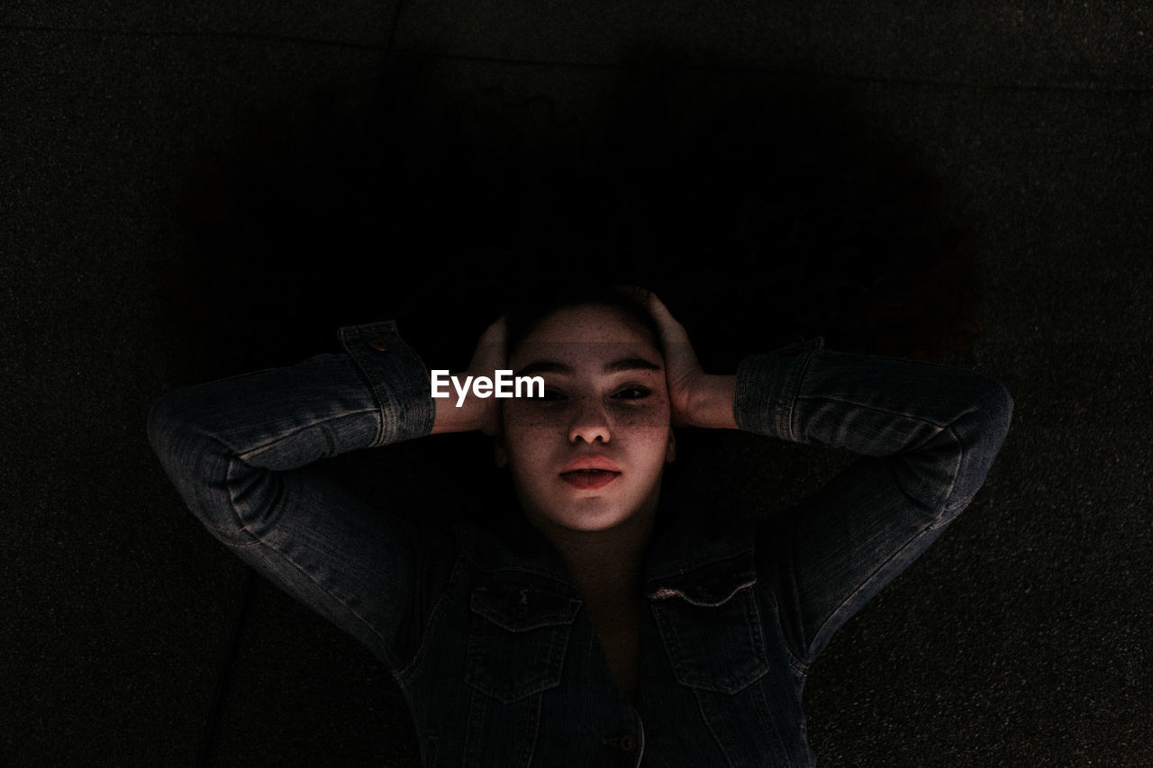 PORTRAIT OF TEENAGE GIRL IN BLACK BACKGROUND