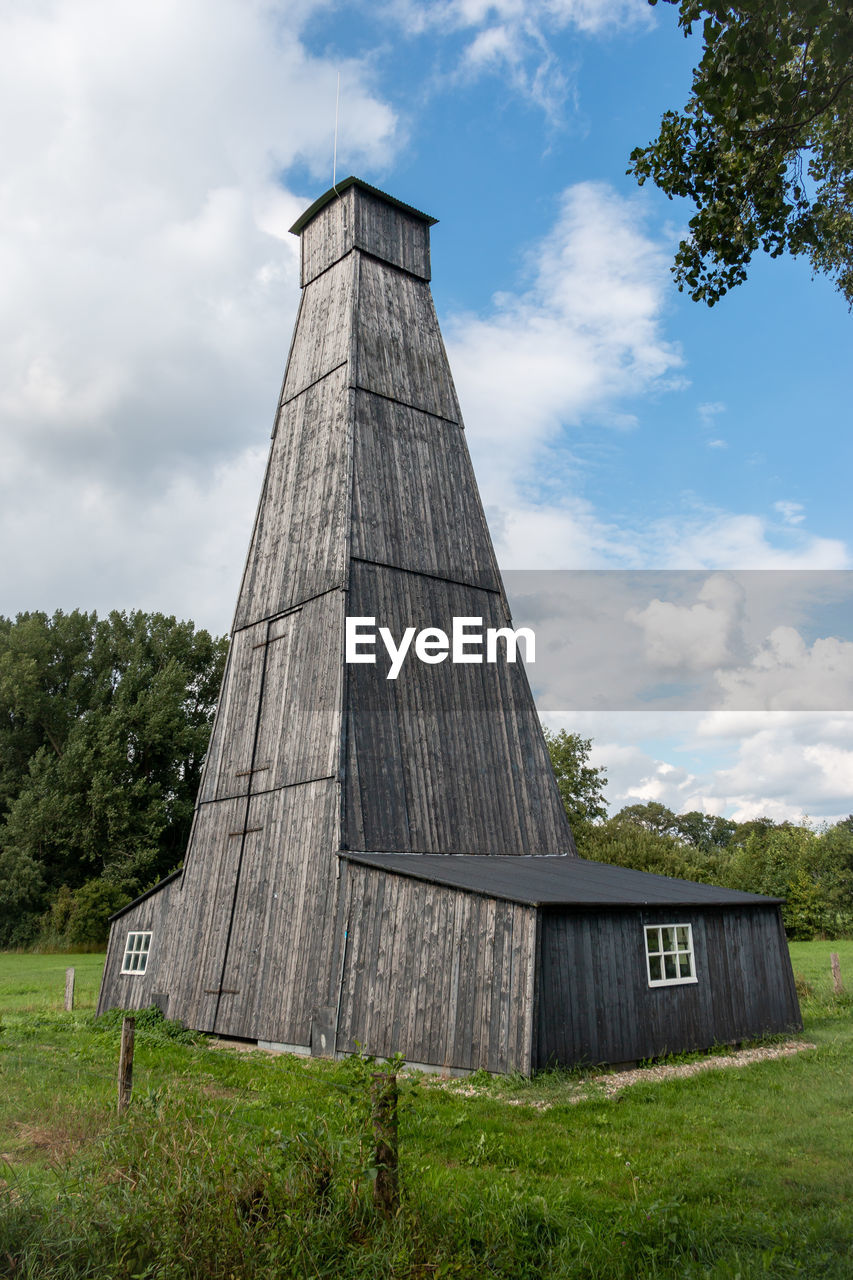 LOW ANGLE VIEW OF BUILDING BY TREES AGAINST SKY