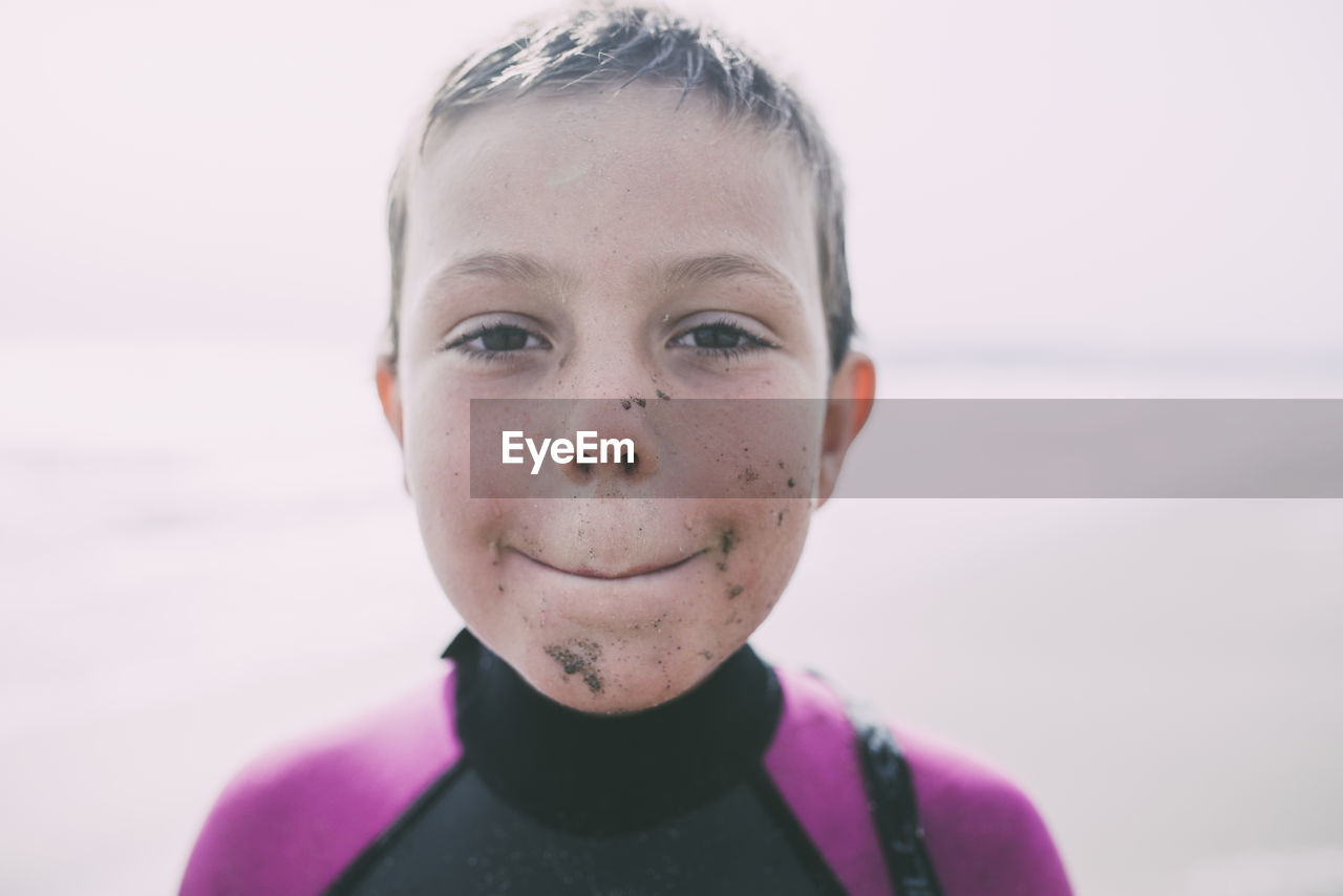 Close-up portrait of boy with messy face standing at beach during sunny day