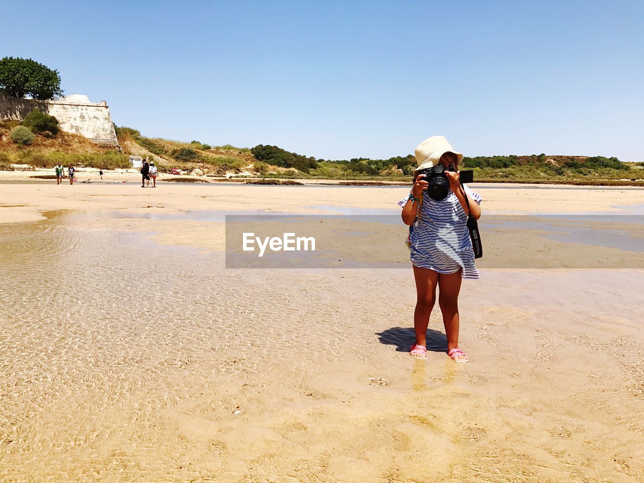 WOMAN STANDING AT BEACH AGAINST CLEAR SKY