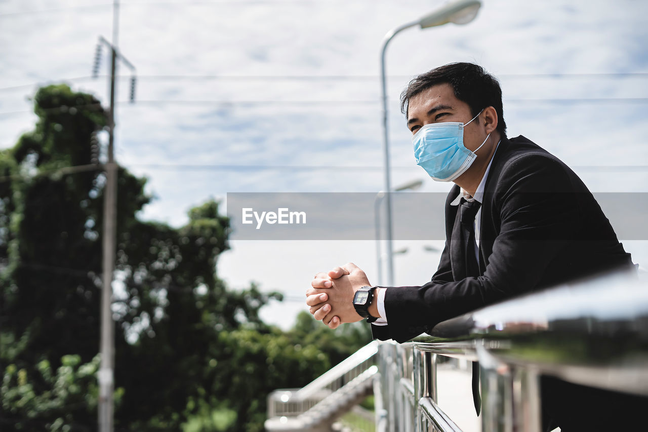 Asian businessman holding briefcase walking on overpass looking outside