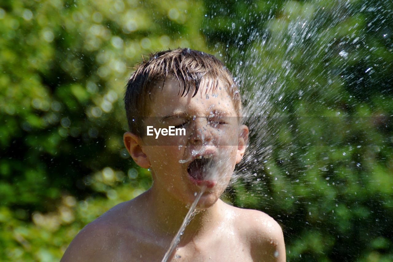 PORTRAIT OF SHIRTLESS BOY WITH WATER IN MOUTH