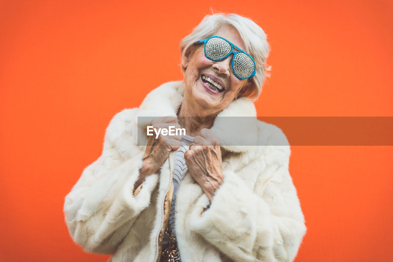 Portrait of smiling woman standing against red background