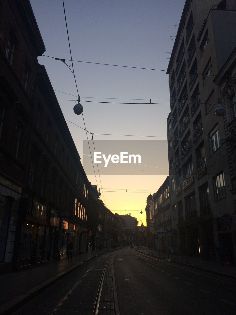 Road by city against sky at sunset