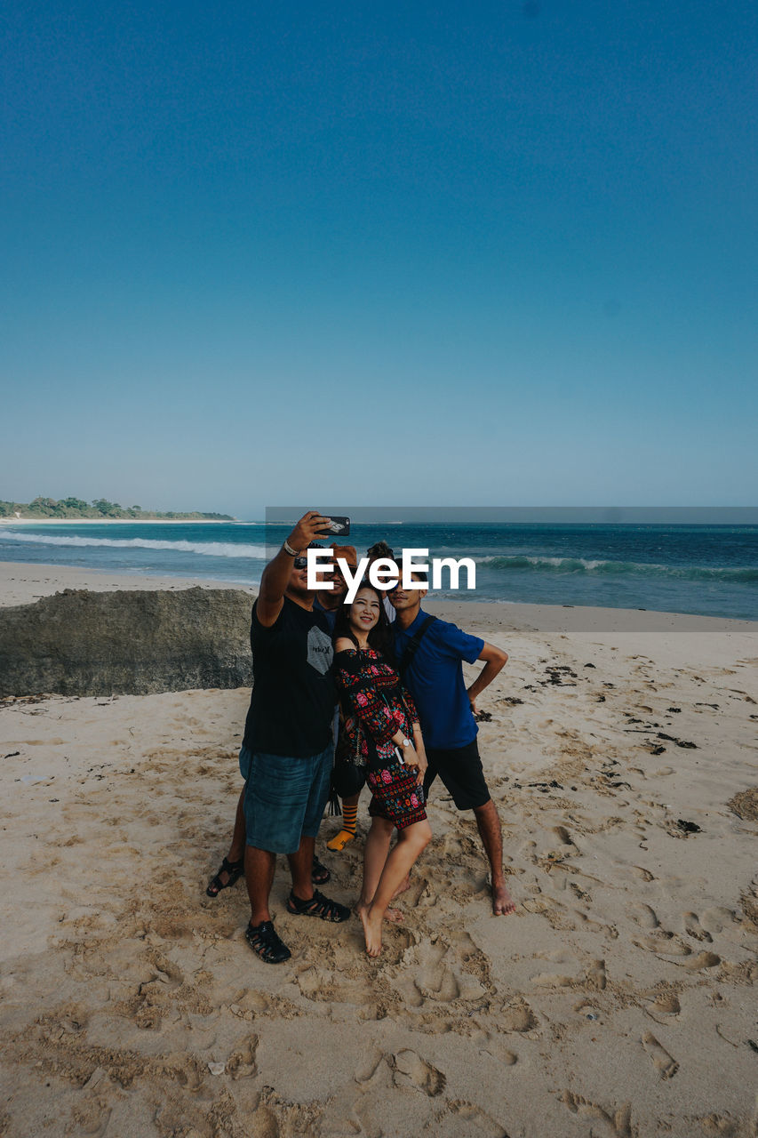 PORTRAIT OF PEOPLE ON BEACH AGAINST SEA