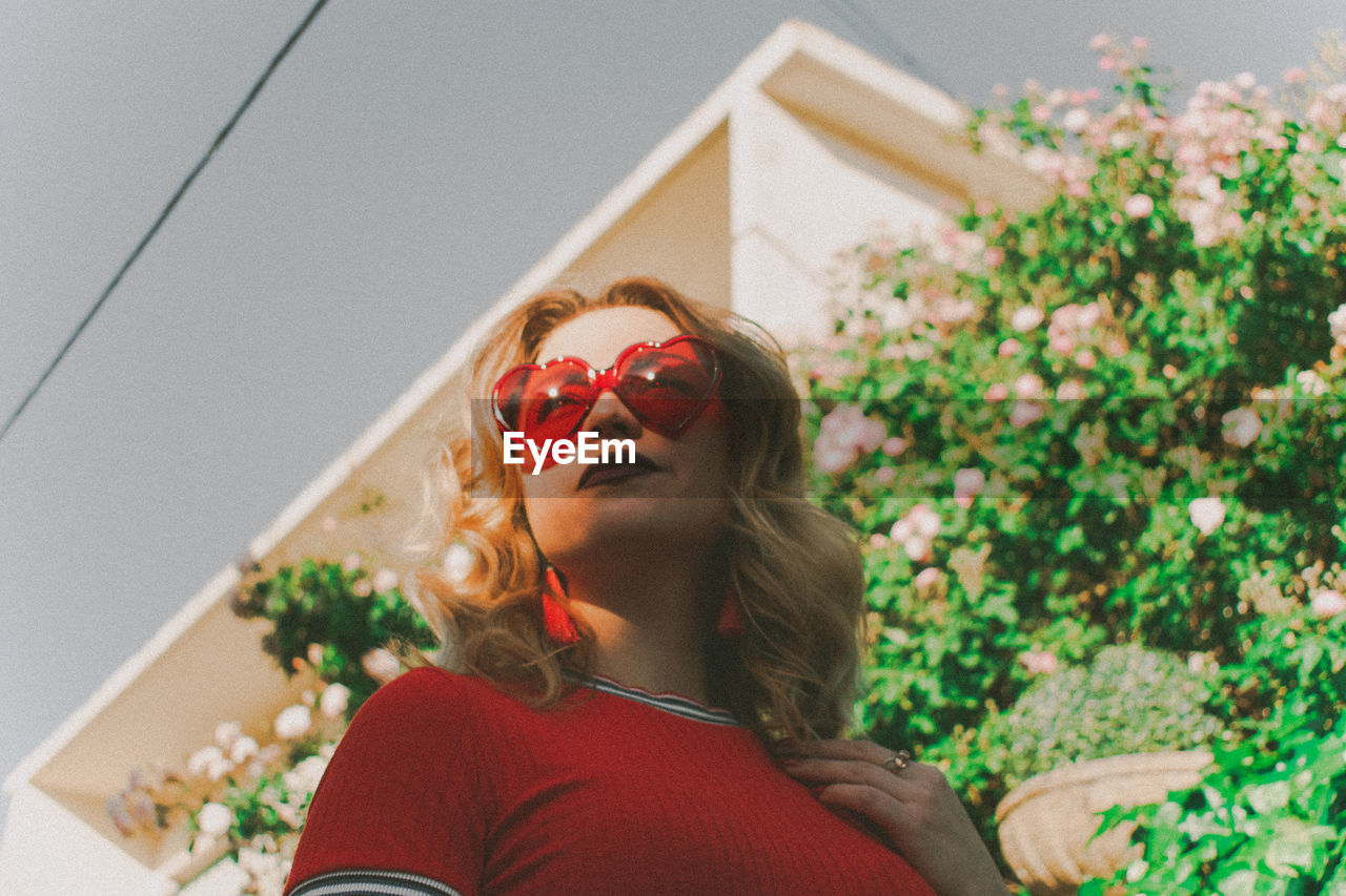 PORTRAIT OF WOMAN WEARING SUNGLASSES OUTDOORS