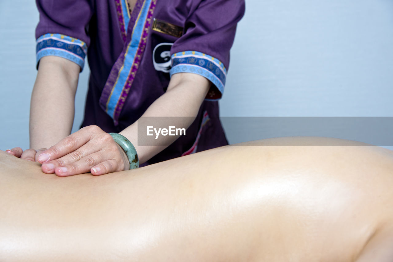 Midsection of massage therapist massaging woman