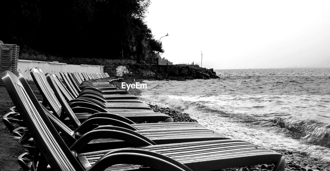 Deck chairs on beach against clear sky