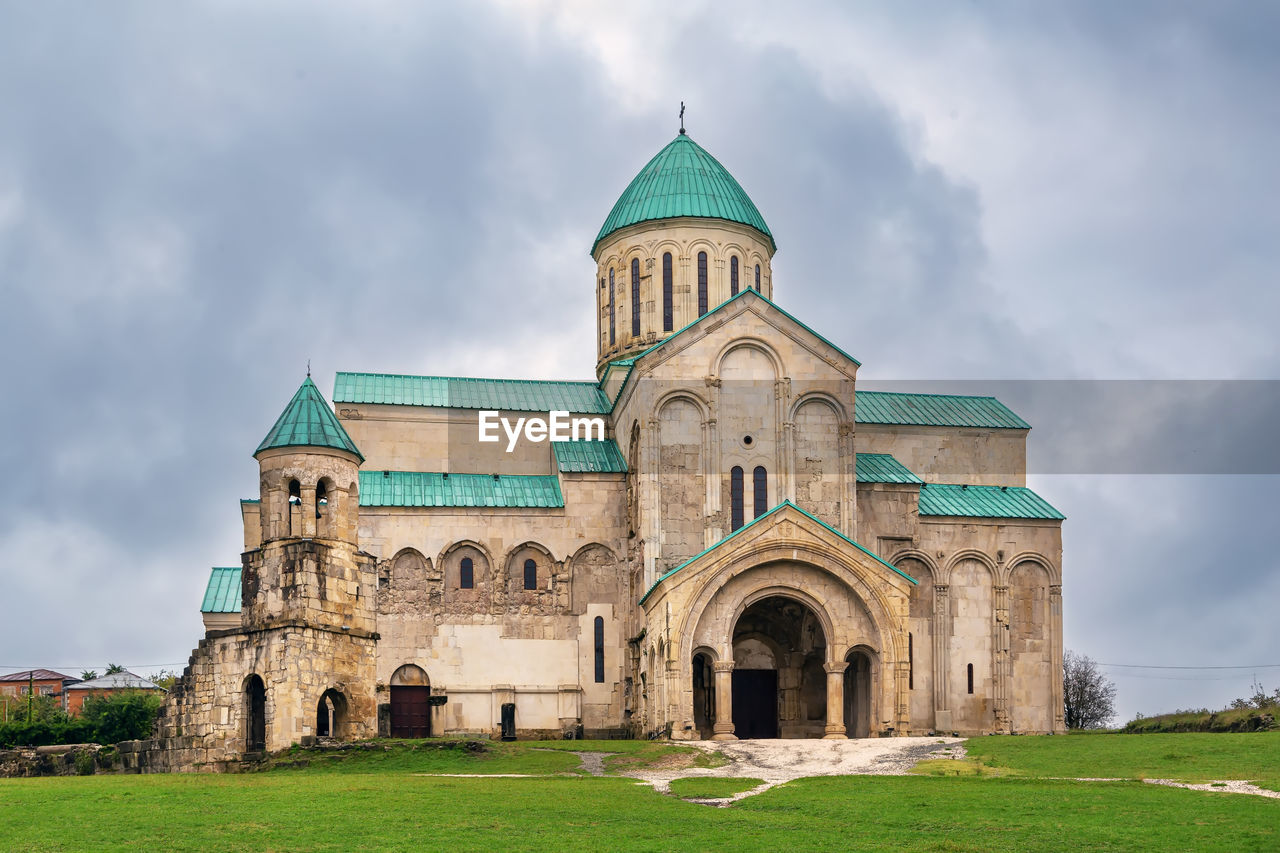 architecture, built structure, building exterior, sky, building, religion, cloud, travel destinations, place of worship, nature, grass, history, belief, the past, spirituality, travel, plant, tourism, green, no people, outdoors, abbey, landmark, landscape, day, facade, blue, tower, old, worship, historic site