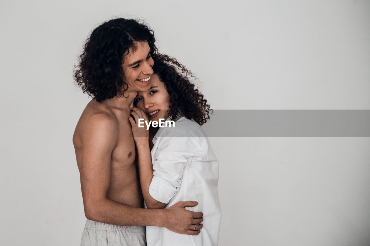 Happy heterosexual couple man and woman embracing white background