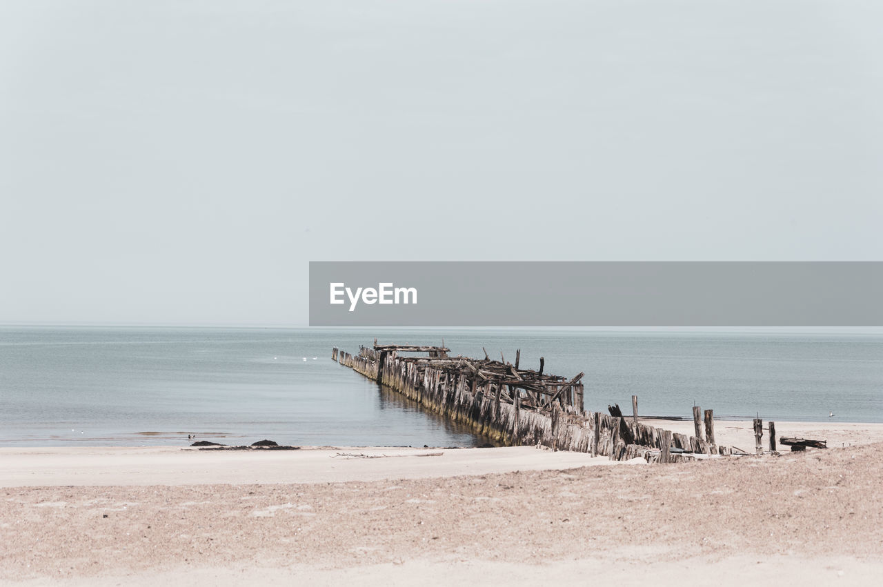 Wooden posts on beach against clear sky