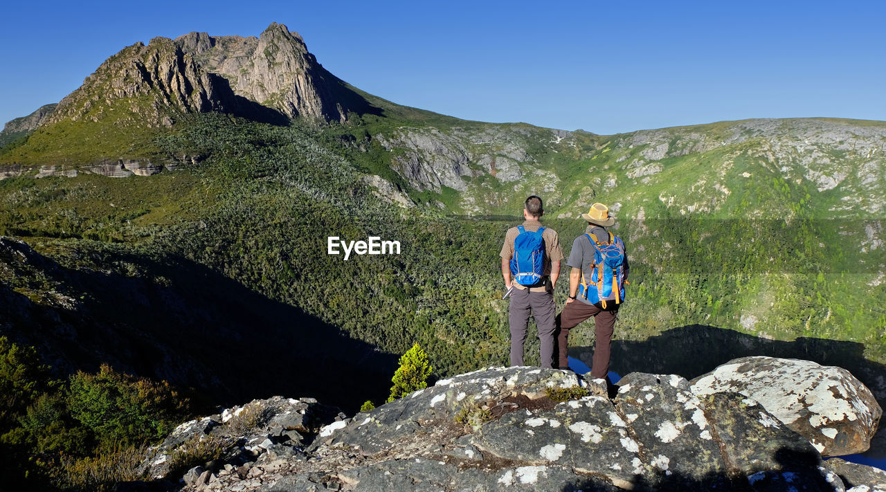 Rear view of male hikers standing against mountains