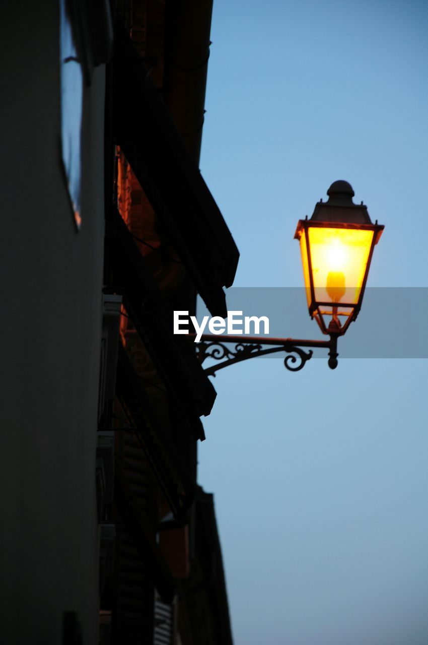 LOW ANGLE VIEW OF ILLUMINATED STREET LIGHTS AT DUSK