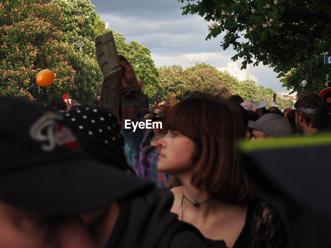 CLOSE-UP OF YOUNG WOMAN WITH BALLOONS AT TREES