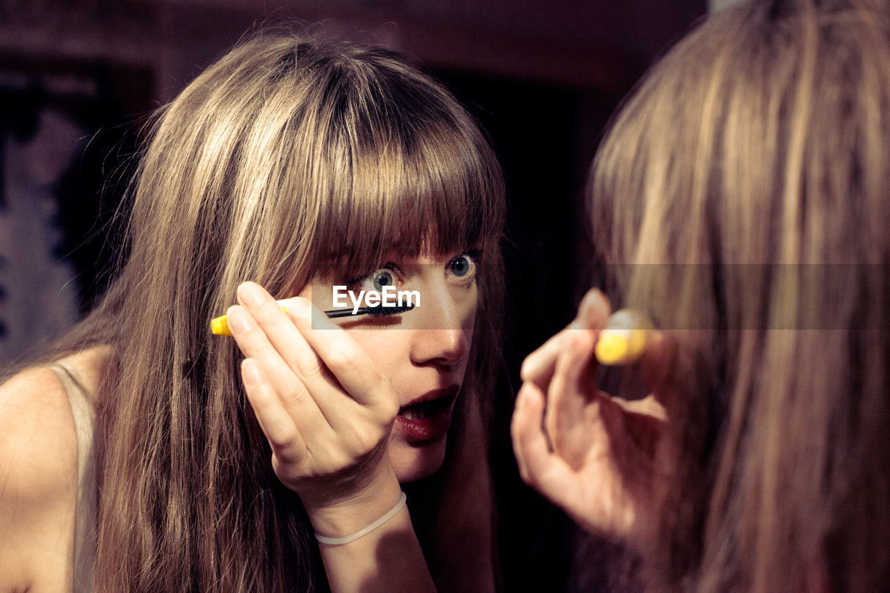 Woman applying mascara at home