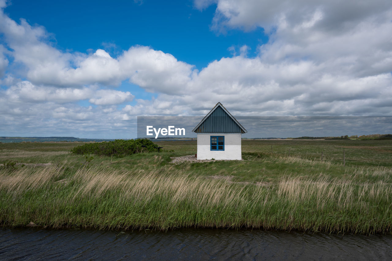 cloud, sky, architecture, built structure, building, horizon, building exterior, landscape, land, grass, prairie, rural area, nature, environment, plain, plant, house, no people, natural environment, scenics - nature, field, rural scene, sea, beach, coast, hut, grassland, hill, non-urban scene, outdoors, wood, beauty in nature, tranquility, remote, water, residential district, road, day, farm, wind, blue, tranquil scene, coastline, travel destinations, shore, steppe, green, agricultural building