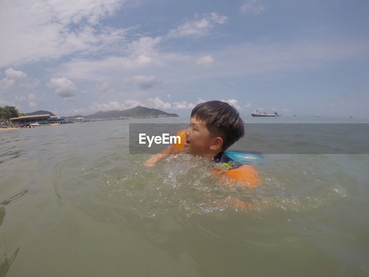 Boy swimming in sea against sky