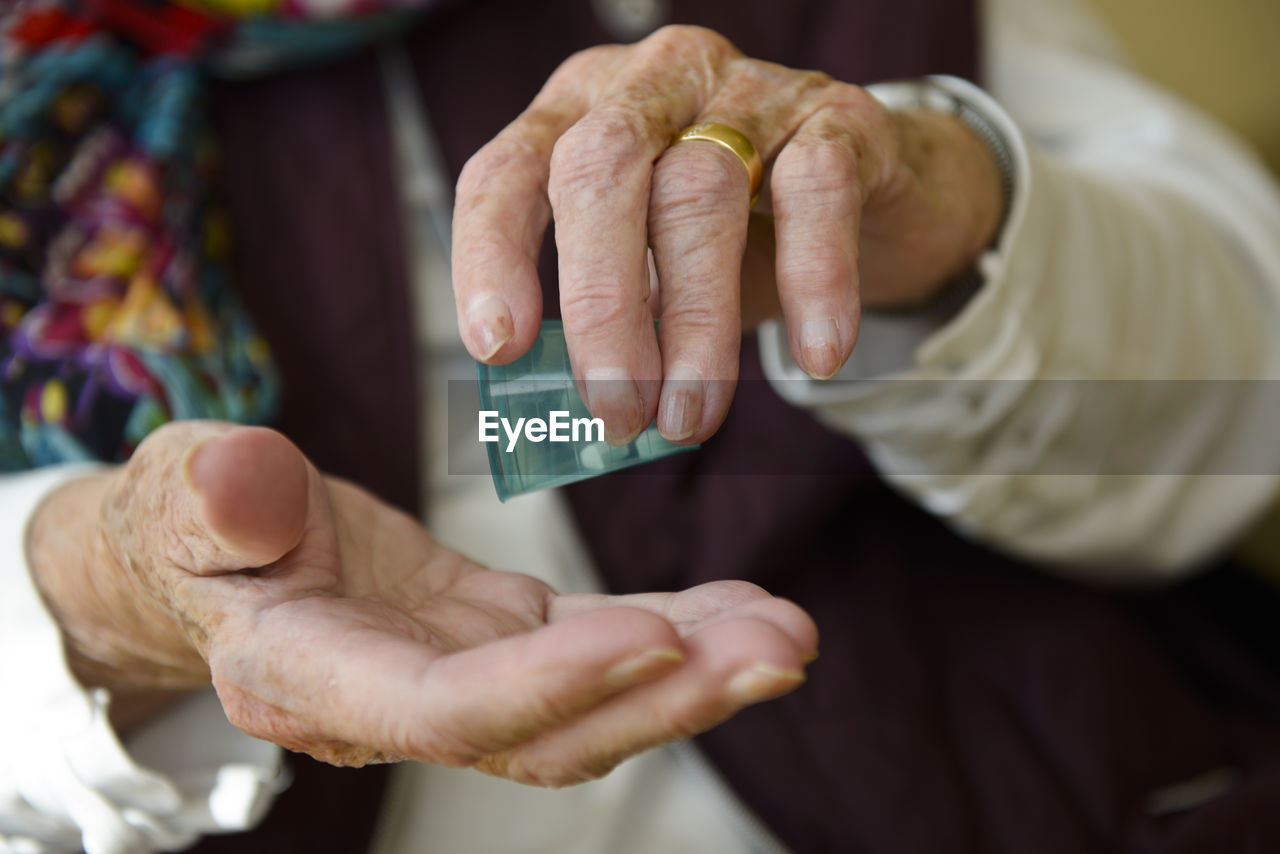 Midsection of senior woman taking medicine at home