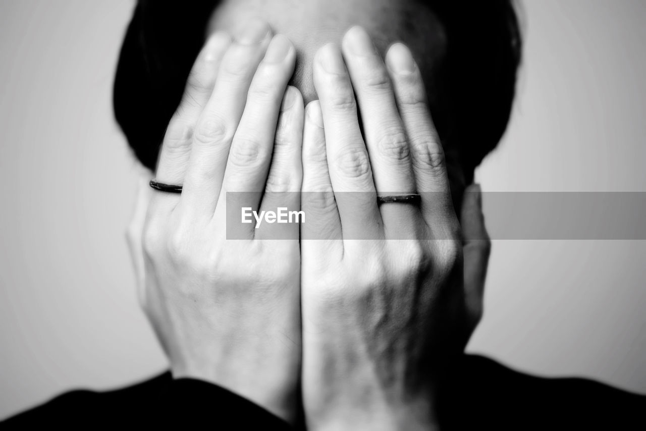 Close-up of woman covering face with hands