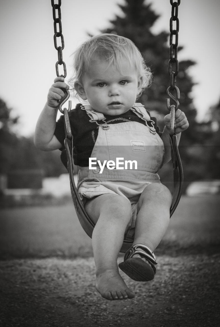 Full length portrait of baby boy on swing at playground