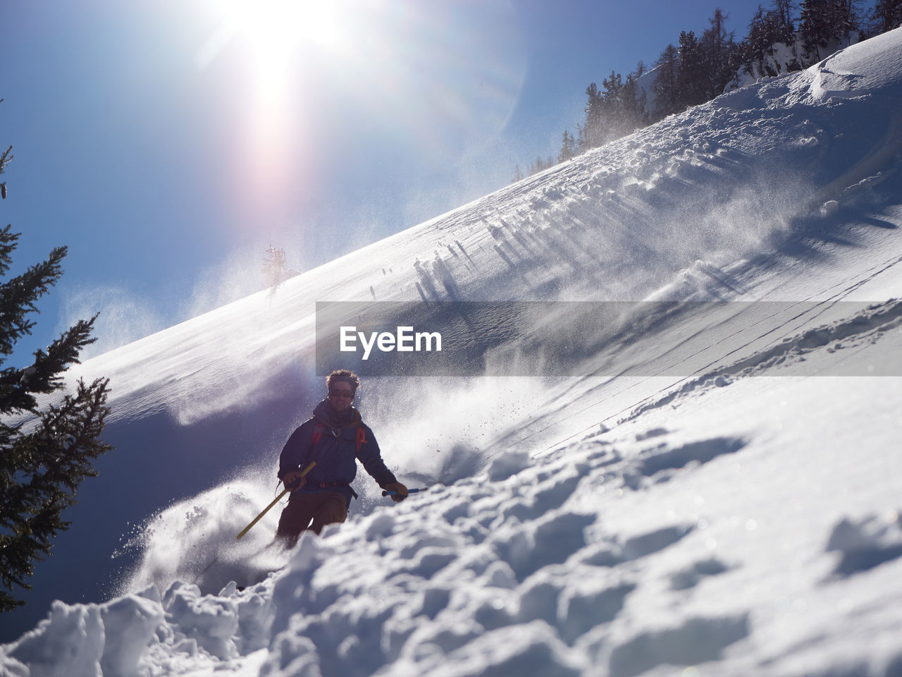 Man skiing in powder backlit by sun