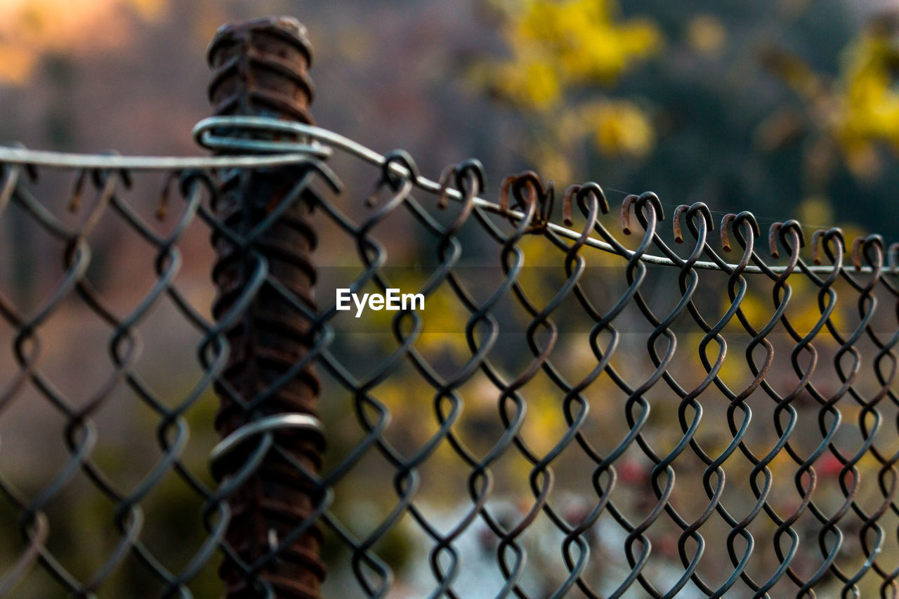 CLOSE-UP OF METALLIC CHAINLINK FENCE AGAINST SKY