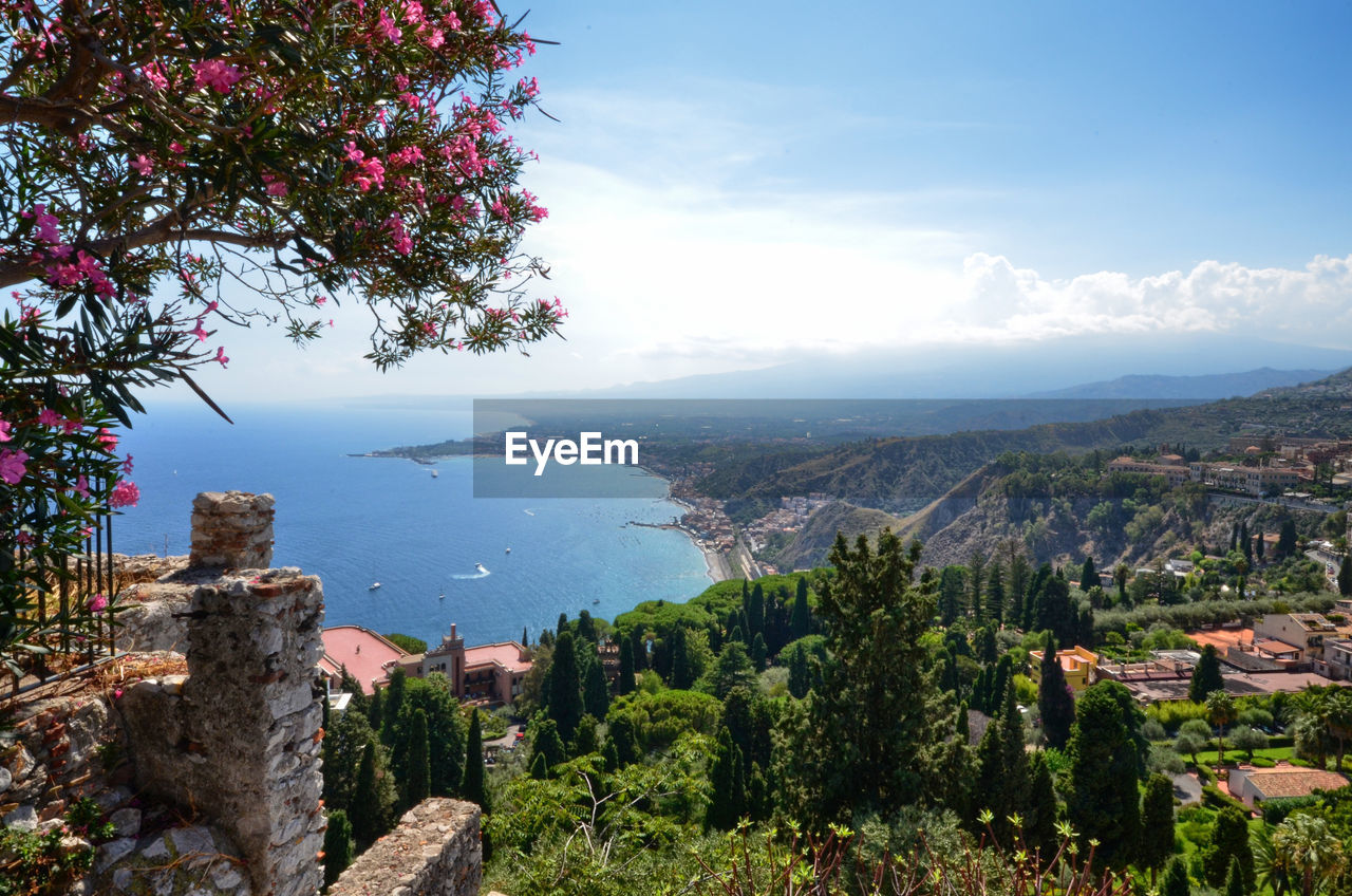 Aerial view of townscape by sea against sky