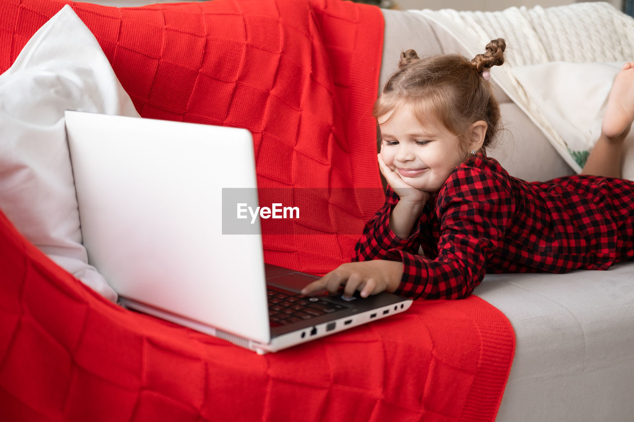 midsection of woman using laptop while sitting on sofa at home