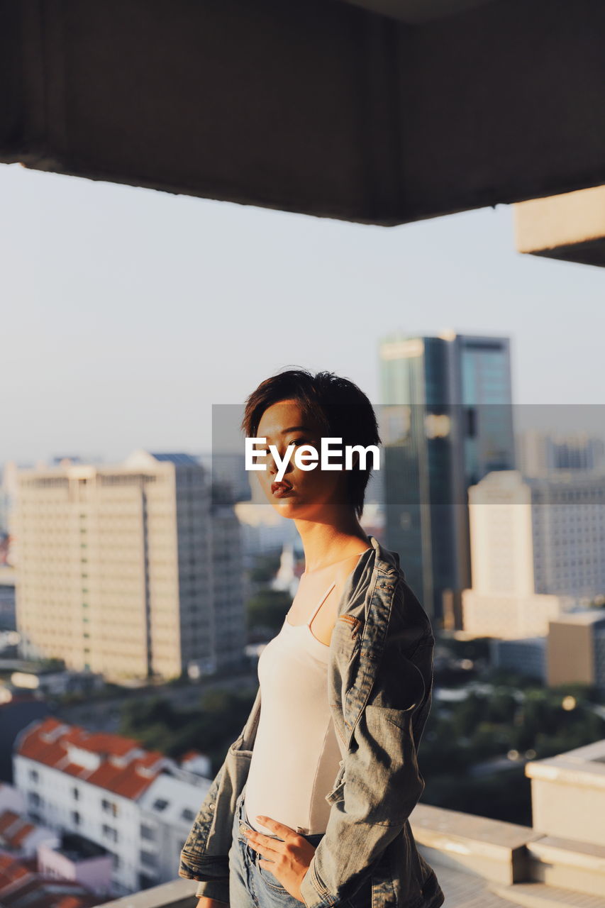 Portrait of woman standing against buildings in city