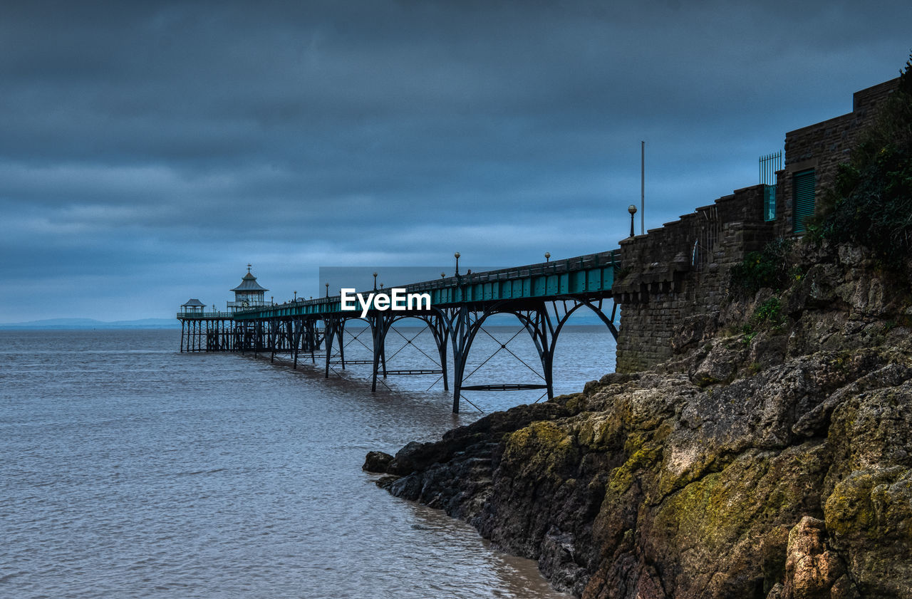 Bridge over sea against sky at dusk