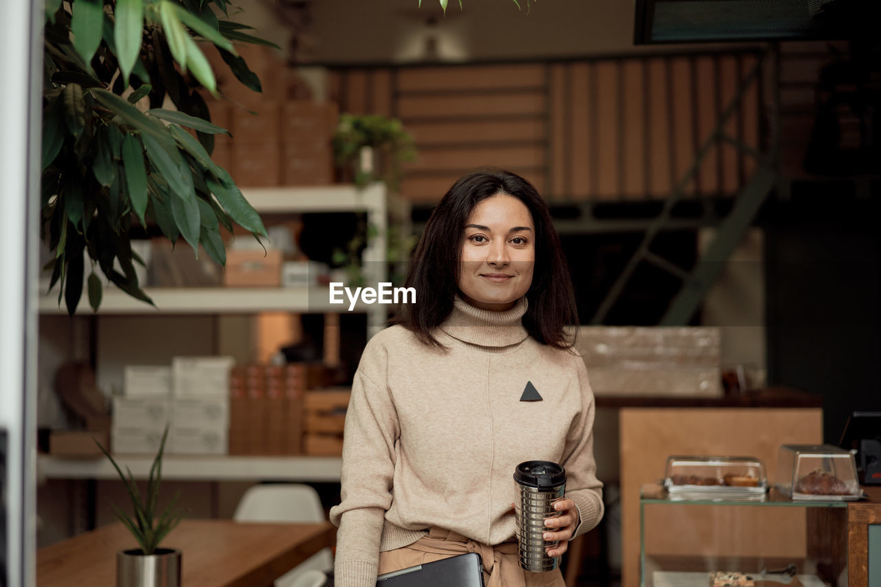 Portrait of woman holding coffee cup at cafe