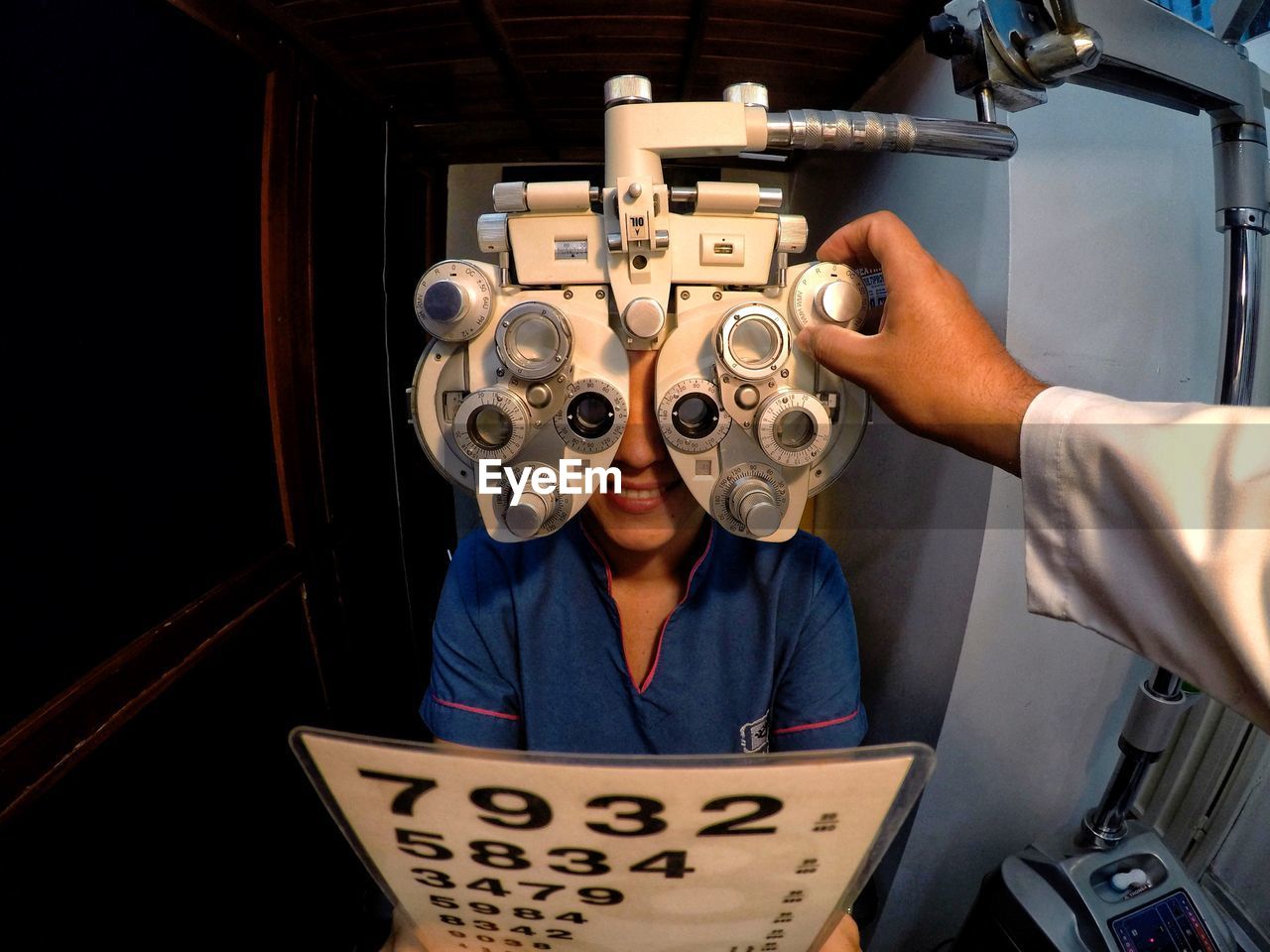 Cropped hand of doctor examining patient eyes using optical instrument